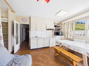 A compact kitchen with white cabinets, a microwave, and a sink. There's a wooden bench and a table with a heart-patterned tablecloth. - Charming studio at the slopes - 5 guests (Les Gets)