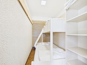 A bunk bed room with a wooden slat wall, white bedding, and a white ceiling light. - Charming studio at the slopes - 5 guests (Les Gets)