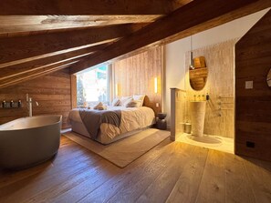A bedroom with a large bathtub, a wooden ceiling, and a view of the outside. - Exceptional Chalet in Vars – 21 guests, 450 sqm, 3 suites (Vars)
