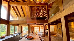 A spacious wooden cabin with a large dining area, a kitchen with a central island, and large windows offering a view of the forest. - Exceptional Chalet in Vars – 21 guests, 450 sqm, 3 suites (Vars)