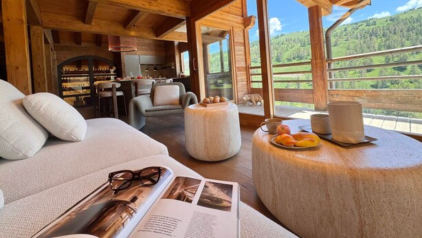 A cozy wooden cabin interior with a dining area, a sofa, and a view of the outdoors. - Exceptional Chalet in Vars – 21 guests, 450 sqm, 3 suites (Vars)