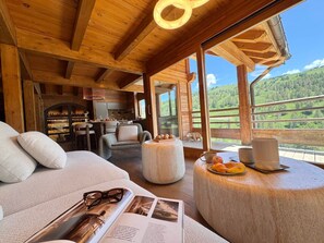 A cozy wooden cabin interior with a dining area, a sofa, and a view of the outdoors. - Exceptional Chalet in Vars – 21 guests, 450 sqm, 3 suites (Vars)