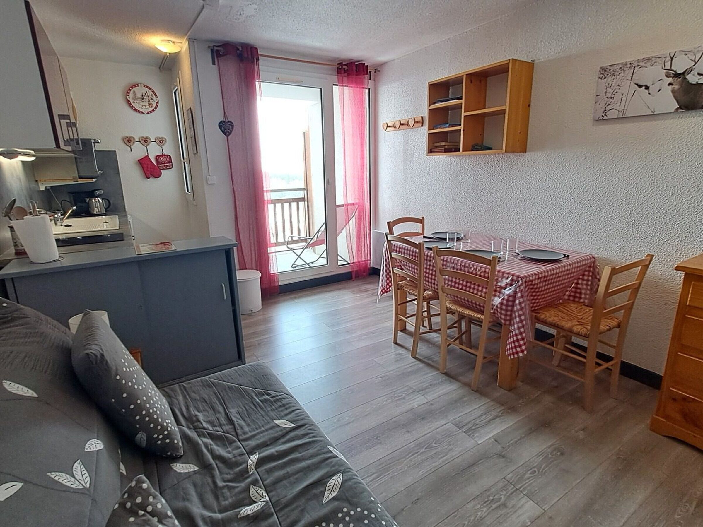 A cozy living area with a sofa, dining table, chairs, and a kitchen area with a sink and cabinets.