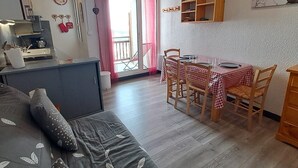 Una sala acogedora con sofá, mesa de comedor, sillas y una cocina con fregadero y armarios.