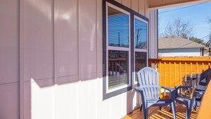 A covered porch with two windows, a wooden deck, and two Adirondack chairs. - Elegant 4br/3ba Gem Near Downtown & The Alamo (San Antonio)