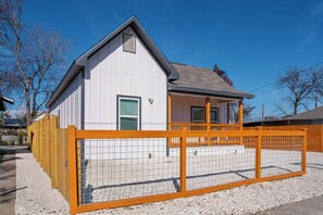 A single-story building with a white exterior, a grey roof, and a fenced front yard. - Elegant 4br/3ba Gem Near Downtown & The Alamo (San Antonio)