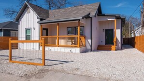 A single-story building with a porch, a fenced area, and a gravel driveway. - Elegant 4br/3ba Gem Near Downtown & The Alamo (San Antonio)