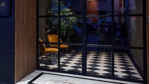 A hotel entrance with a checkered floor, a wooden ceiling, and a glass door. - Innapartments Avenida 60 (Aveiro)