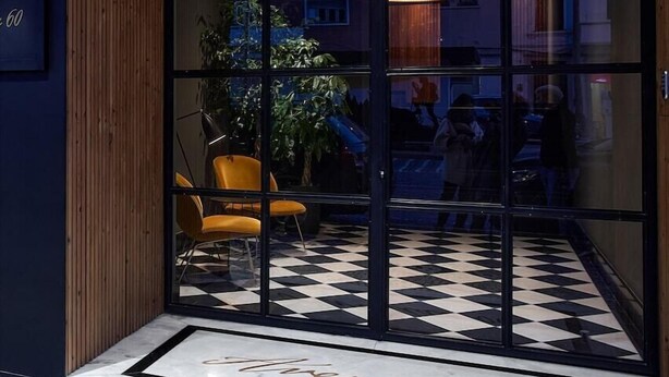 A hotel entrance with a checkered floor, a wooden ceiling, and a glass door. - Innapartments Avenida 60 (Aveiro)