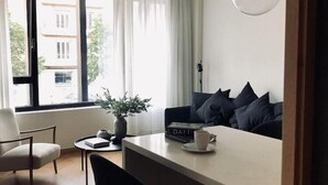 A modern living space with a dining area, a sofa with cushions, a coffee table, and a potted plant. - Innapartments Avenida 60 (Aveiro)