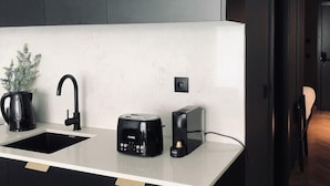A modern kitchen with a black countertop, a coffee maker, a toaster, and a black cabinet. - Innapartments Avenida 60 (Aveiro)