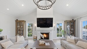 A spacious living room with a fireplace, a large flat-screen TV, and two sofas. - Wagon Wheeler 6 Bed 4 Bath Private Pool Close to Gulf & Village Sleeps 12 (Boca Grande)