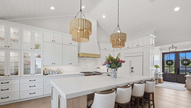 A spacious kitchen with white cabinetry, a large island with bar stools, and hanging wicker chandeliers. - Wagon Wheeler 6 Bed 4 Bath Private Pool Close to Gulf & Village Sleeps 12 (Boca Grande)