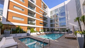 A modern building with a rooftop pool, lounge chairs, and potted plants. - Luxury Hollywood Condo, 2 King Suites, Pool (Los Angeles)