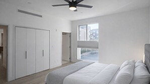 A bedroom with a bed, a ceiling fan, a window with a view of buildings, and a wardrobe. - Luxury Hollywood Condo, 2 King Suites, Pool (Los Angeles)