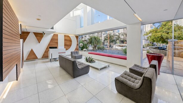 A modern lobby with a reception desk, seating area, and large windows offering views of the street. - Luxury Hollywood Condo, 2 King Suites, Pool (Los Angeles)