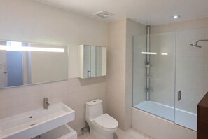 A modern bathroom with a glass-enclosed shower, a white sink, and a toilet.