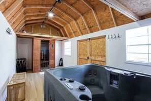 Une salle de spa dotée d’une grande baignoire, de poutres en bois au plafond et d’une porte en bois.