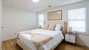 Una camera da letto con un letto, un comodino, una lampada e un quadro appeso al muro.