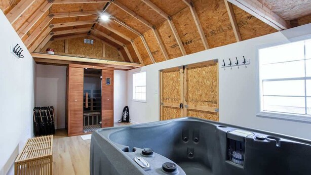 Una stanza spa con una vasca da bagno ampia, travi in legno al soffitto e una porta in legno.