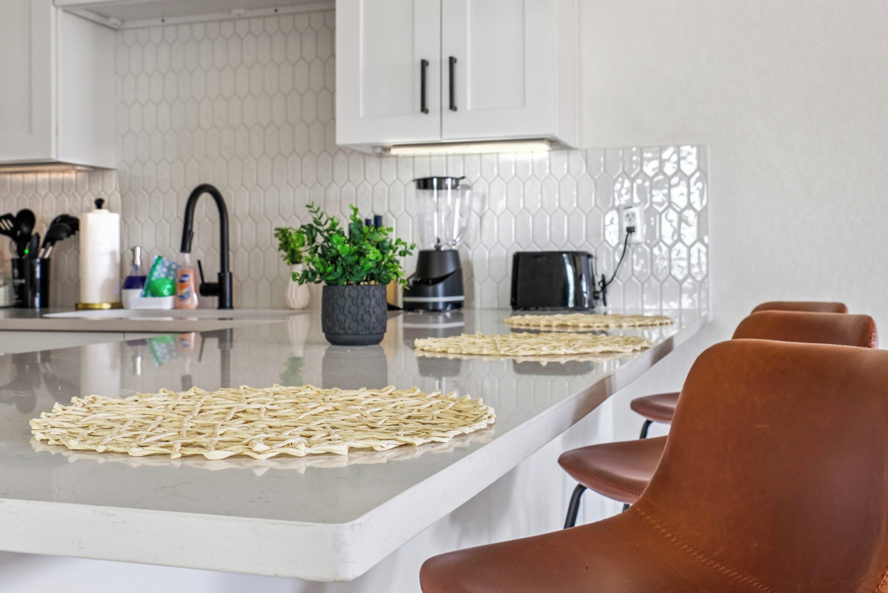 A kitchen with a central island, a toaster, a blender, and a potted plant.