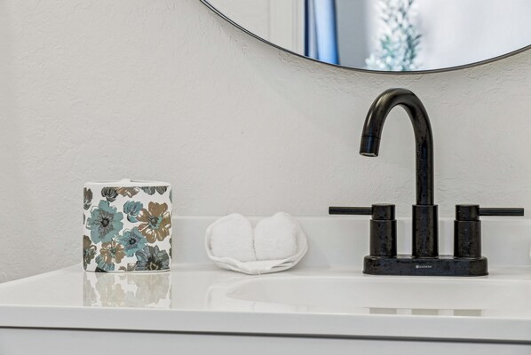 A bathroom sink with a black faucet, a floral-patterned mug, and a white towel. - Sleek 3 Bedroom /2 Bath Just 5 Minutes to Downtown (San Antonio)