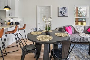 A modern kitchen with white cabinets, a black countertop, and a dining area with a round table and chairs. - Sleek 3 Bedroom /2 Bath Just 5 Minutes to Downtown (San Antonio)