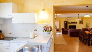 A modern kitchen with a built-in stove, a large island with a sink, and a dining area with a fireplace. - Villa Vernier (Istria - Kringa) (Kringa)