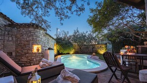 Un muro de piedra, un jacuzzi, sillas de descanso y un comedor con mesa y sillas.