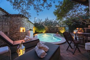 A stone wall, a hot tub, lounge chairs, and a dining area with a table and chairs. - Villa Ulika Krnica (Istria - Krnica) (Krnica)
