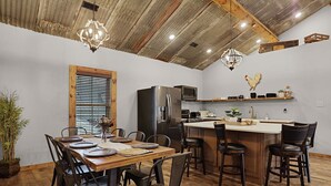 Una cocina moderna con una isla de madera, electrodomésticos de acero inoxidable y un comedor con mesa y sillas de madera.