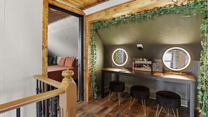 Una habitación con techo de madera, un tocador con dos espejos, un escritorio y dos taburetes negros.