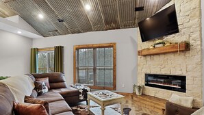 Una sala de estar con chimenea de piedra, sofás de cuero y un televisor de pantalla plana.