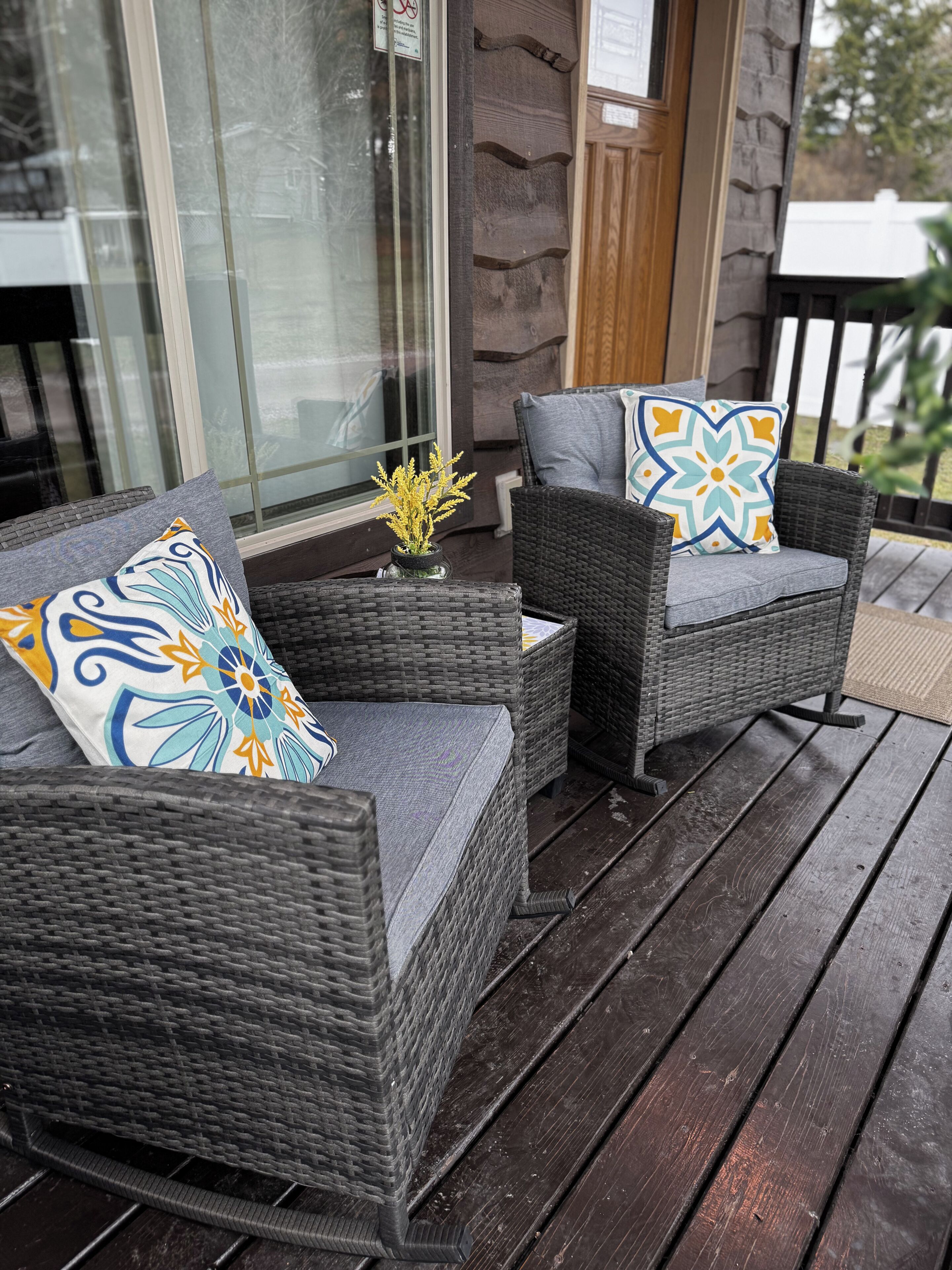 A wicker sofa set with patterned cushions on a wooden deck.