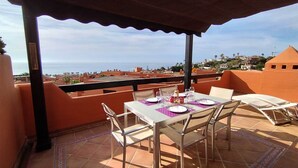 A terrace with a table set for two, overlooking a coastal cityscape. - New Galera Gardens (Estepona)