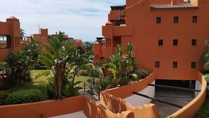 A residential area with orange buildings, a swimming pool, and lush greenery. - New Galera Gardens (Estepona)