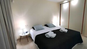 A hotel room with a bed, a bedside table with a lamp, a mirror, and a wardrobe. - New Galera Gardens (Estepona)