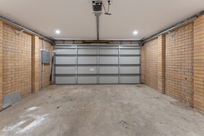 Eine Garage mit einer geschlossenen Metalltür, Ziegelwänden und einem Betonboden.