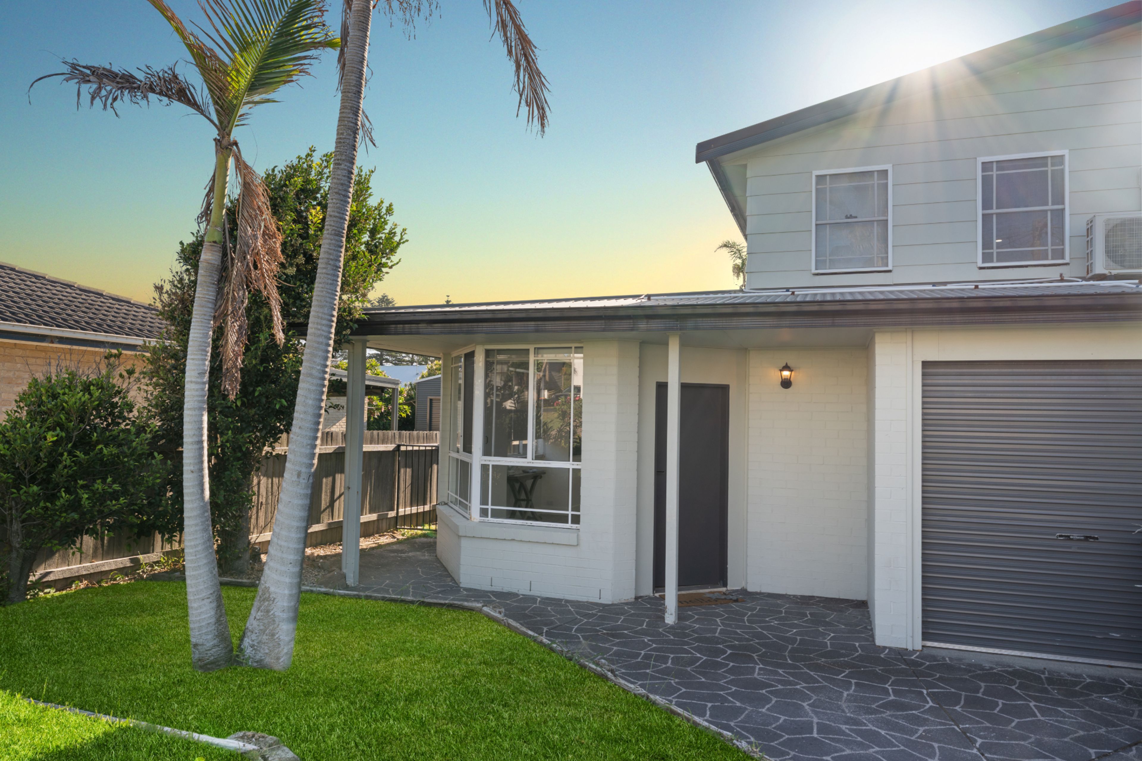 A residential house with a garage, a covered patio, and a lawn.