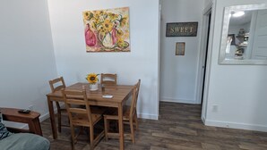 Un coin repas avec une table en bois, des chaises et un tableau accroché au mur.