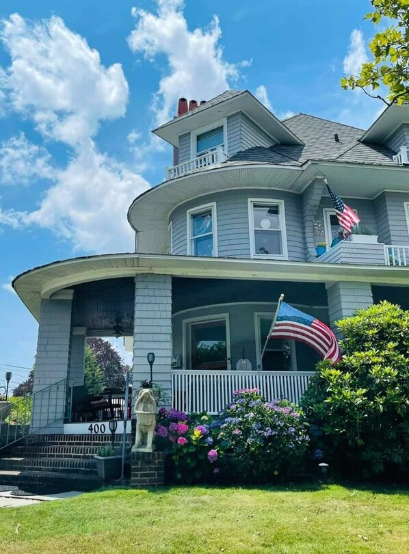 Une maison à deux étages avec un porche, une statue et un drapeau.