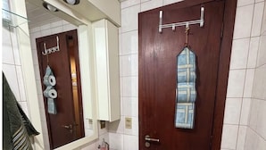 Ein Badezimmer mit Waschbecken, Spiegel, Handtuchhalter und einer Tür, an der ein Handtuch hängt.