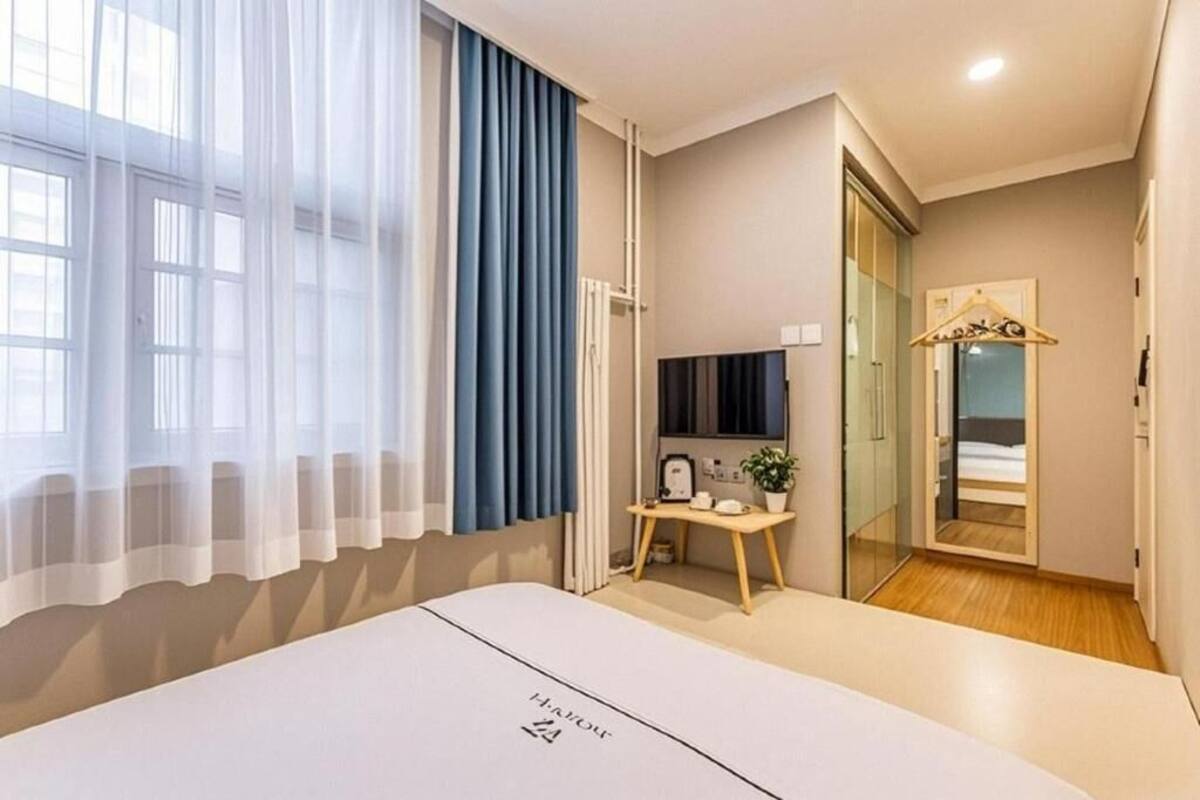 A hotel room with a bed, a desk, a TV, a mirror, and a wardrobe.