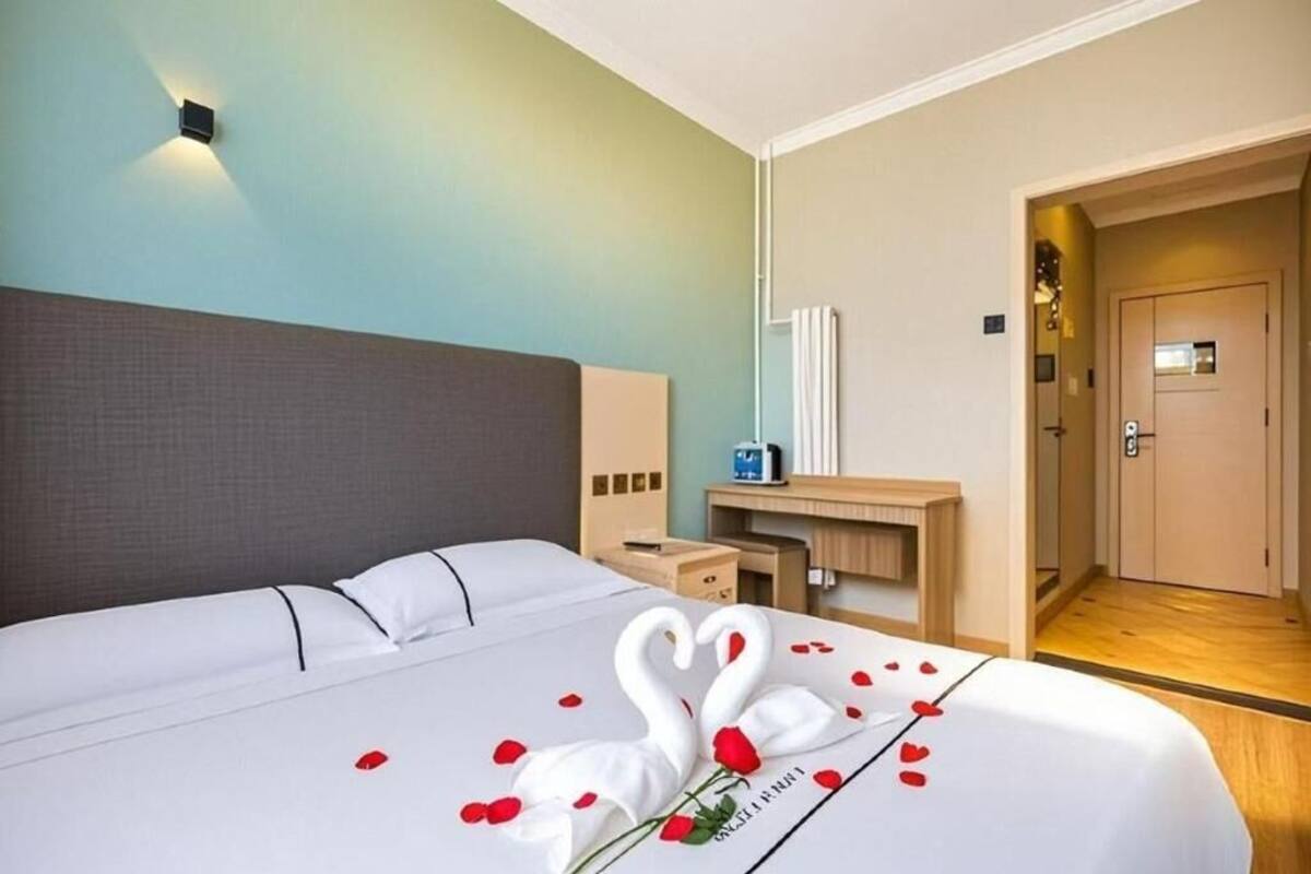 A hotel room with a large bed, a bedside table, a mirror, and a door leading to another room.