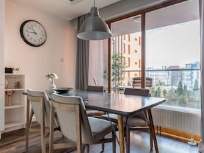 A modern dining area with a large table, chairs, a hanging light fixture, and a clock on the wall. - Motława Downtown Superior Apartment (Gdańsk)