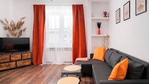 En moderne stue med sofa, skammel og fjernsyn på et træskab.