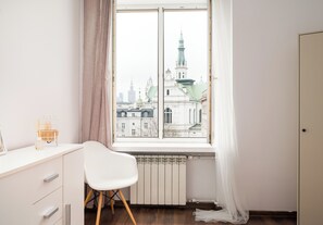 Ein Zimmer mit Blick auf die Stadtlandschaft, ein weißer Schreibtisch, ein Sessel und eine Heizung.