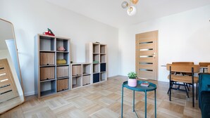 A room with wooden flooring, a dining table with chairs, a small round table with a plant, and built-in shelving units.