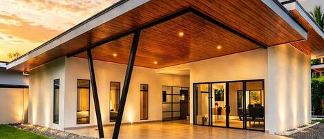 A modern house with a sloped roof, large glass windows, and a gravel driveway.