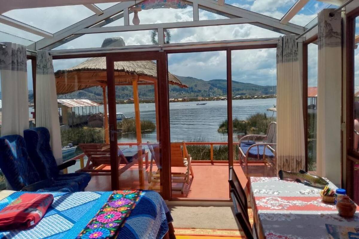 Ein Zimmer mit einer großen Glasdoor, die auf einen Balkon mit Blick auf ein Gewässer und Hügel führt.